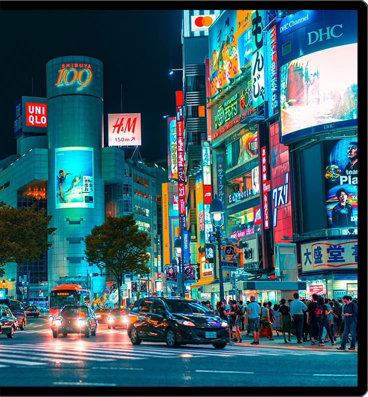 Nachtelijk straatbeeld met felle neonreclames in HDR op een Kuycon-monitor